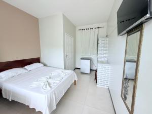 a white bedroom with a bed and a mirror at Pousada Acalanto in Aracaju