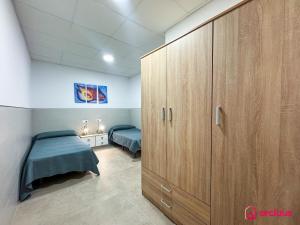 a bedroom with two beds and a large wooden cabinet at El Piso Bajo in San Juan de Moró