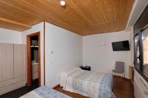 a bedroom with two beds and a television in a room at Hotel Restaurante Port d'Ager in Àger