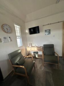 a living room with two chairs and a clock on the wall at Windy Nook - The Contemporary Tiny Home in Saint Philip
