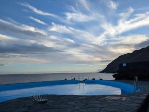 a blue swimming pool on the beach with the ocean at Apartamento La Caleta El Hierro Island terrace with incredible views in La Caleta