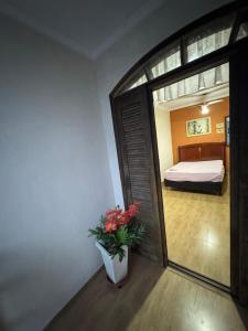 a room with a bedroom with a bed and a vase with flowers at Predinho do Guaratuba in Guaratuba +1 photo