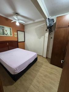 a bedroom with a bed and a flat screen tv at Predinho do Guaratuba in Guaratuba