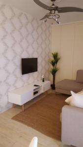 Una sala de estar con un televisor de pantalla plana en una pared. en The Grand Orchid Guesthouse, en Durban