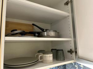 a cupboard with a stove and pots and pans at Résidence P&C Studio calme & cosy proche Paris - Neuilly-sur-Marne in Neuilly-sur-Marne