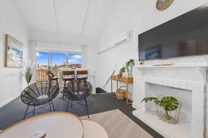a living room with a fireplace and a table and chairs at Sunset Seas in West Beach in West Beach