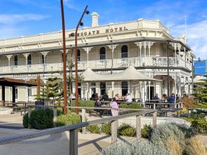a large white building with people sitting in front of it at Sunset Seas in West Beach in West Beach