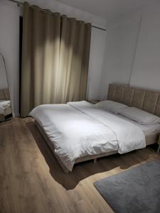 a bedroom with a large bed with white sheets at Tirana Apartment in Kashari