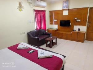 a hotel room with a bed and a chair and a television at Hotel Raaj Inn Service Apartment in Chennai