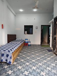 a bedroom with a bed with a blue and white blanket at Shiv Lehri Homestay in Ujjain