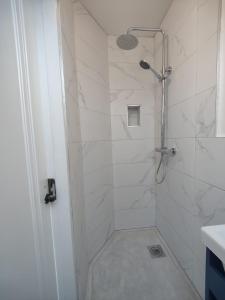 a bathroom with a shower with white marble tiles at Lighthouse view in Garryvoe +21 photos