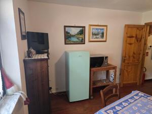 a room with a refrigerator and a desk with a computer at Le Grenier Morgex La Ruine in Morgex