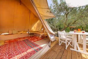 a tent with a bed and a table on a deck at Odyssey Eco Farm Glamping in Galatas