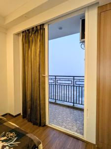a room with a sliding glass door with a balcony at Omaxe Air B&B in Greater Noida