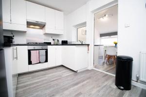 an open kitchen with white cabinets and a table at Afan House by STAE-Homes in Glyncorrwg