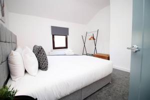 a bedroom with a white bed with pillows and a mirror at Afan House by STAE-Homes in Glyncorrwg