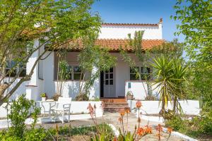 a white house with white chairs and trees at Odyssey Eco Farm Glamping in Galatas