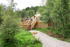 a wooden house with a wooden staircase in the woods at Hazel Tree Yurt - Eavestone Lake in Grantley