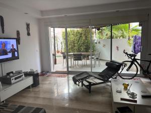 a living room with a chair and a television and a table at Spacious open plan ground floor apartment in Port de Pollensa