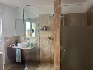 a bathroom with a glass shower with a sink at Spacious open plan ground floor apartment in Port de Pollensa +7 photos