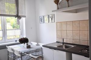 cocina blanca con fregadero y mesa en Apartament Rosa en Jelenia Góra