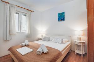 a white bedroom with a bed with towels on it at Apartment Bernarda in Igrane