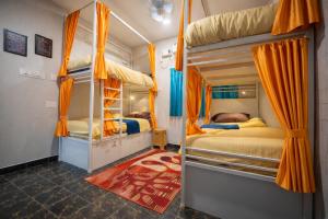 a bedroom with two bunk beds with orange curtains at Rayzen Stays & Backpackers Hostel in Chennai