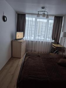 a bedroom with a bed and a desk with a laptop at Cozy Žemaitės gatvė in Telšiai
