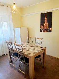 a dining room table with four chairs and a painting on the wall at Apartment PER DAY in Vrbas