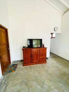 a tv sitting on top of a wooden cabinet in a room at Palms and Paradise Lanka in Marawila