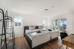 a white bedroom with a large bed and a ladder at Check-In by BeOne RW-N in Rottweil