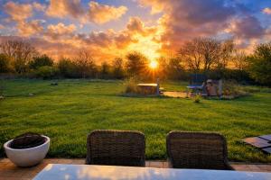a sunset over a field with a table and chairs at Villa Silbermöwe in Trent