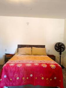 a bedroom with a bed with a red bedspread with flowers at Chalé em Tatajuba in Tatajuba +1 photo