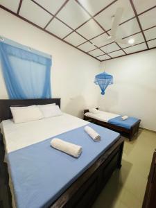 two beds in a room with blue and white at Fourcoock Villa in Kosgoda