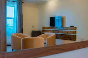a room with two chairs and a flat screen tv at Royal Crown Hotel - Kigali in Kigali