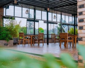 a dining room with tables and chairs and windows at Royal Crown Hotel - Kigali in Kigali