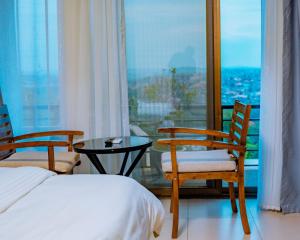 a bedroom with a bed and two chairs and a table at Royal Crown Hotel - Kigali in Kigali +79 photos