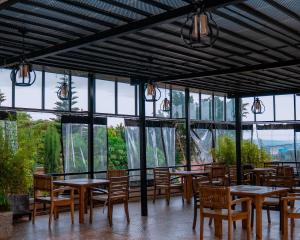 a restaurant with tables and chairs and windows at Royal Crown Hotel - Kigali in Kigali