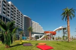 a park with a slide and palm trees in front of a hotel at Grannos Thermal Hotel & Convention Center in Haymana