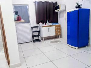 a kitchen with a blue refrigerator and a white tile floor at Condomínio Flamboyant in Pindamonhangaba