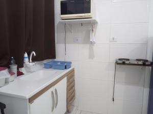 a kitchen with a sink and a microwave on a shelf at Condomínio Flamboyant in Pindamonhangaba +19 photos