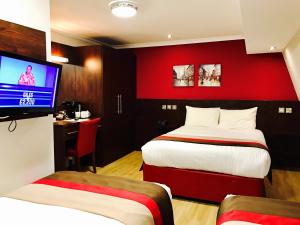 a hotel room with two beds and a flat screen tv at Royal Cambridge Hotel in London