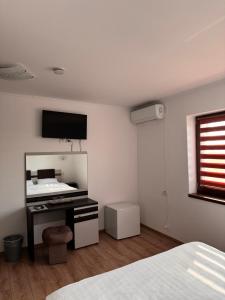 a bedroom with a desk and a sink and a window at Cazare & Restaurant Dalia in Socodor