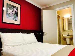 1 dormitorio con cama blanca y pared roja en Royal Cambridge Hotel en Londres