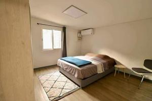 a bedroom with a bed and a chair and a window at La Maison des Cocotiers in Petite Île