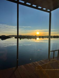 a sunset over a body of water with the sun setting at Titicaca deluxe lodge in Puno