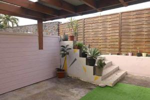 a patio with potted plants on a wall at La Maison des Cocotiers in Petite Île
