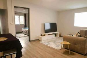 a living room with a couch and a flat screen tv at La Maison des Cocotiers in Petite Île