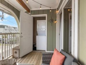 a porch with a couch and a refrigerator on a balcony at Sea The Good condo in Carolina Beach