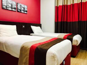 two beds in a room with a red wall at Royal Cambridge Hotel in London